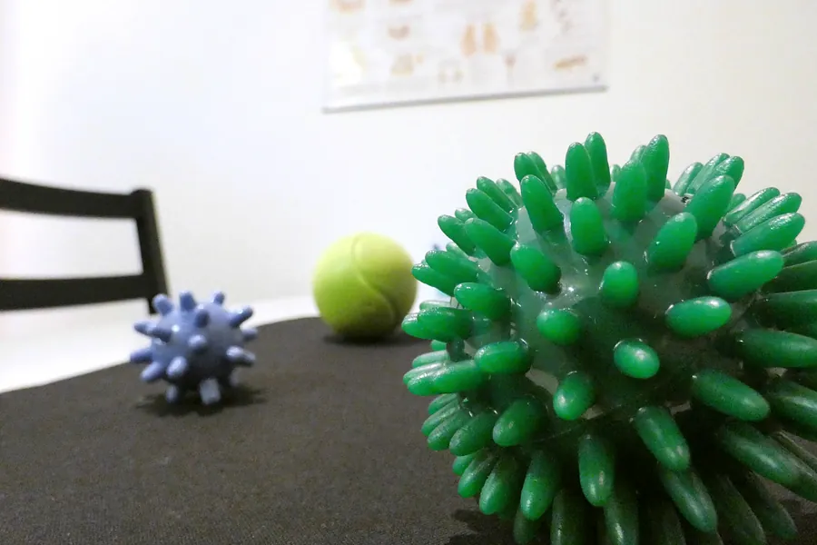 Igelbälle und ein Tennisball als Therapiematerial auf dem Tisch